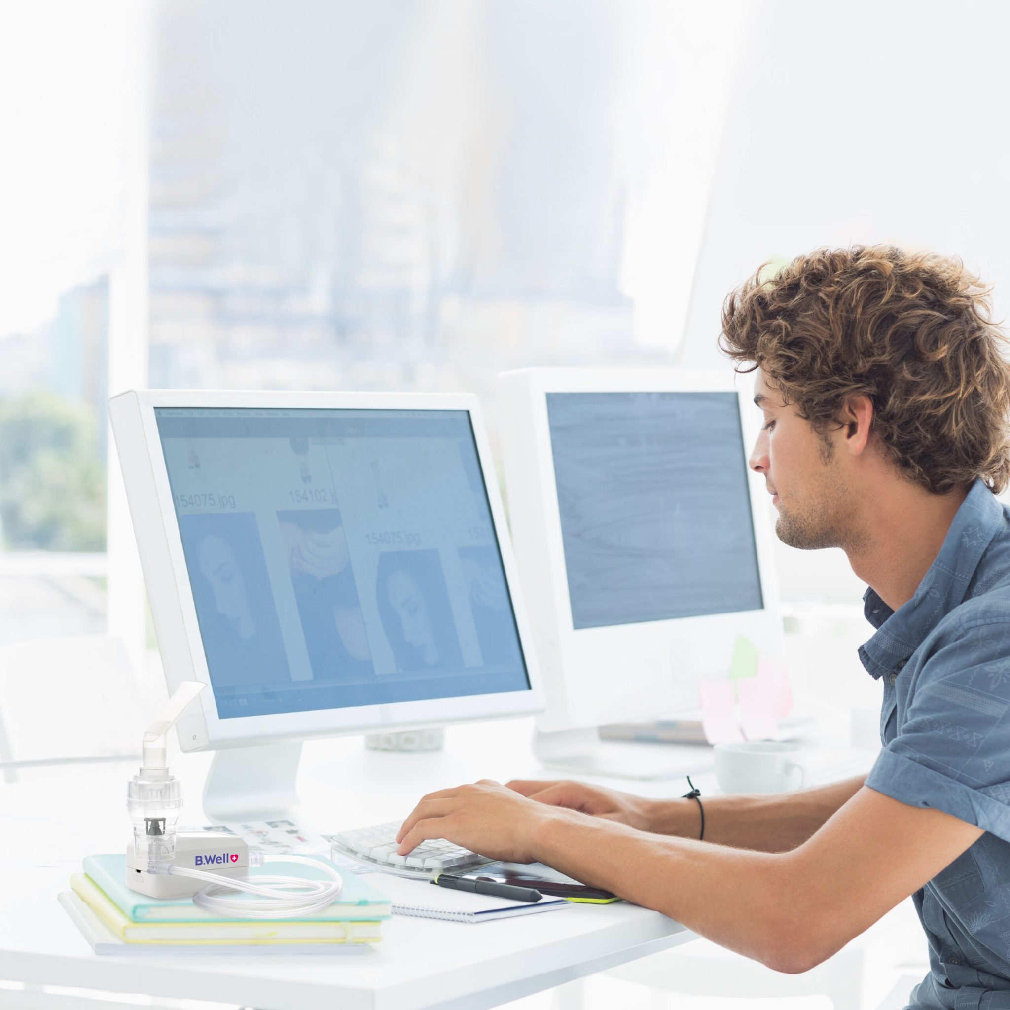 Side view of a concentrated casual young man using computer in a bright office